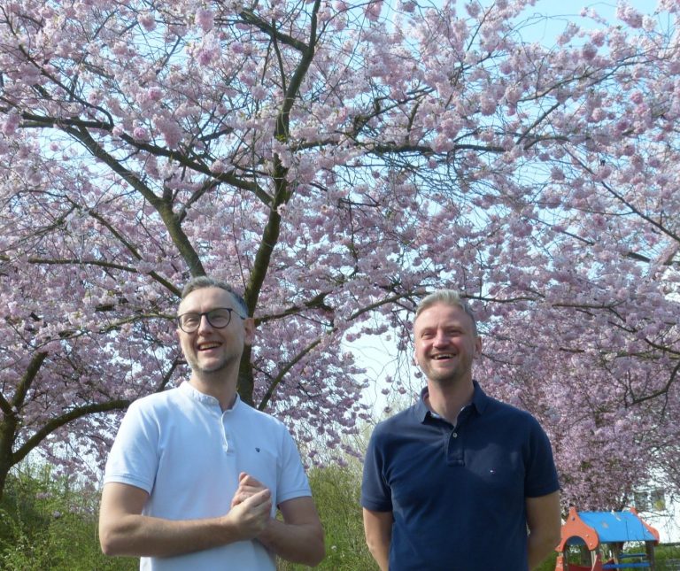 Vasily und Christian Vasily und Christian lächeln vor einem blühenden Kirschbaum